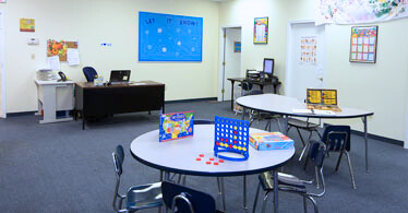 Classroom with round table and Connect4 game in foreground